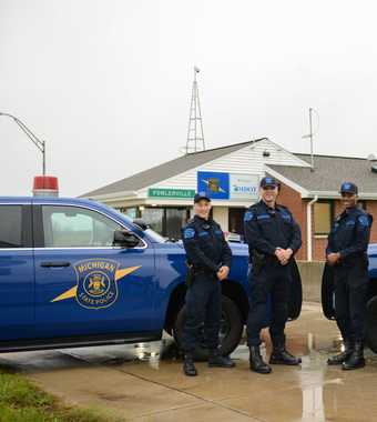 Four Motor Carrier Officers smiling between cruisers at MSP Post